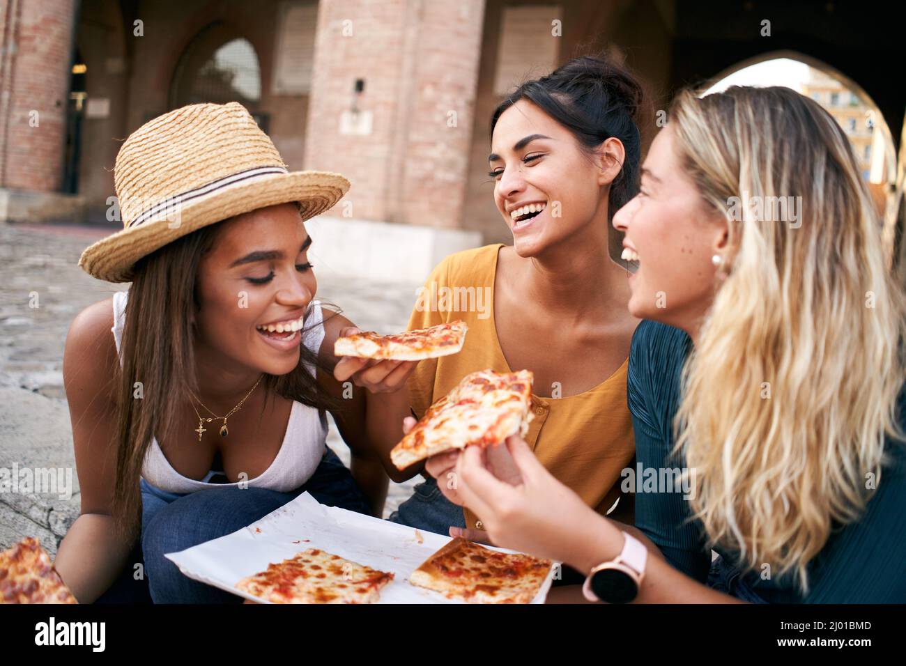 Divertente gruppo di tre amiche che mangiano pizza in città. Le persone che godono week-end e vacanze in estate Foto Stock