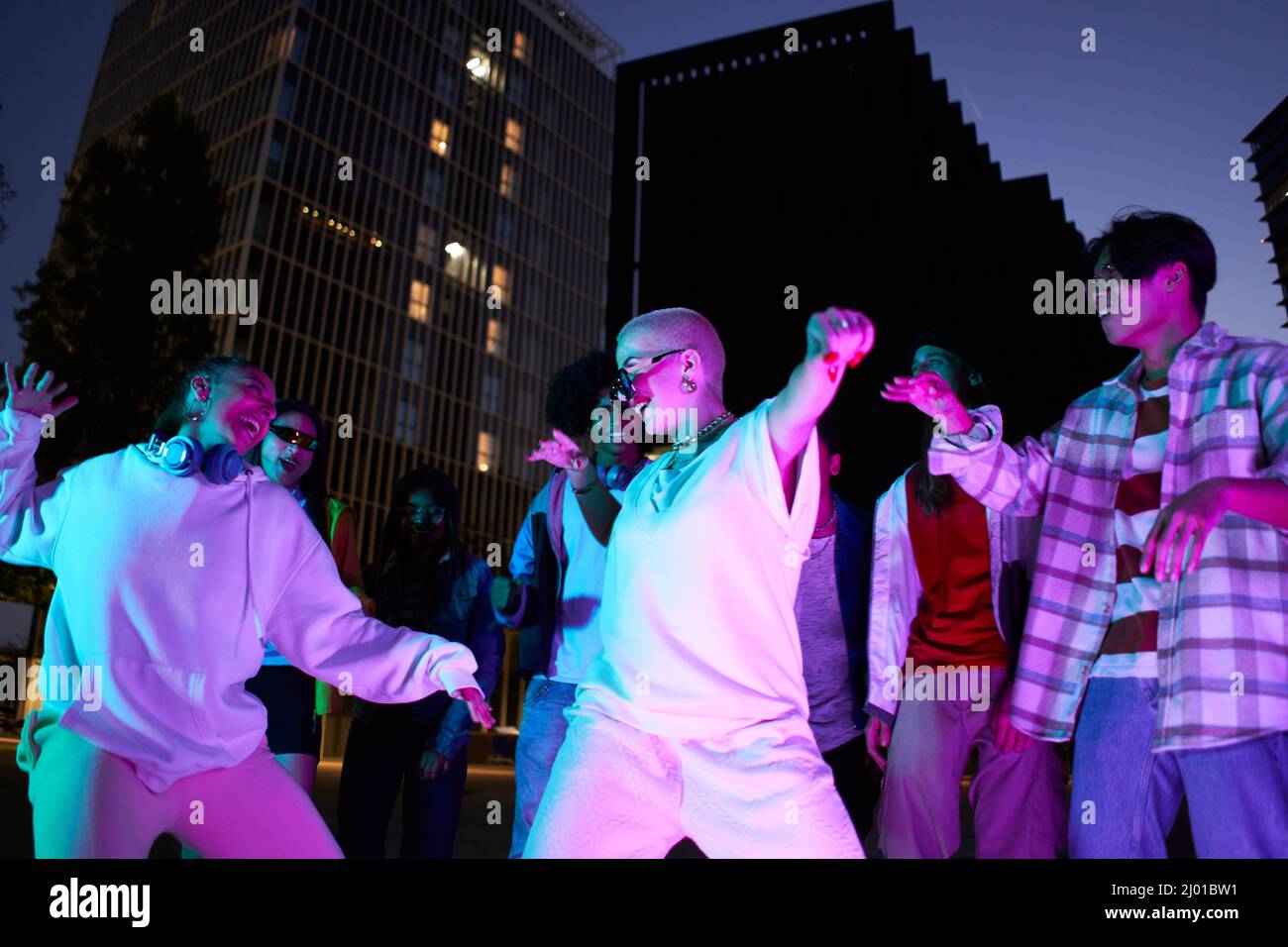 I giovani ballano durante la serata di festa in città. Amici multiculturali moderni che si divertono insieme con la musica Foto Stock