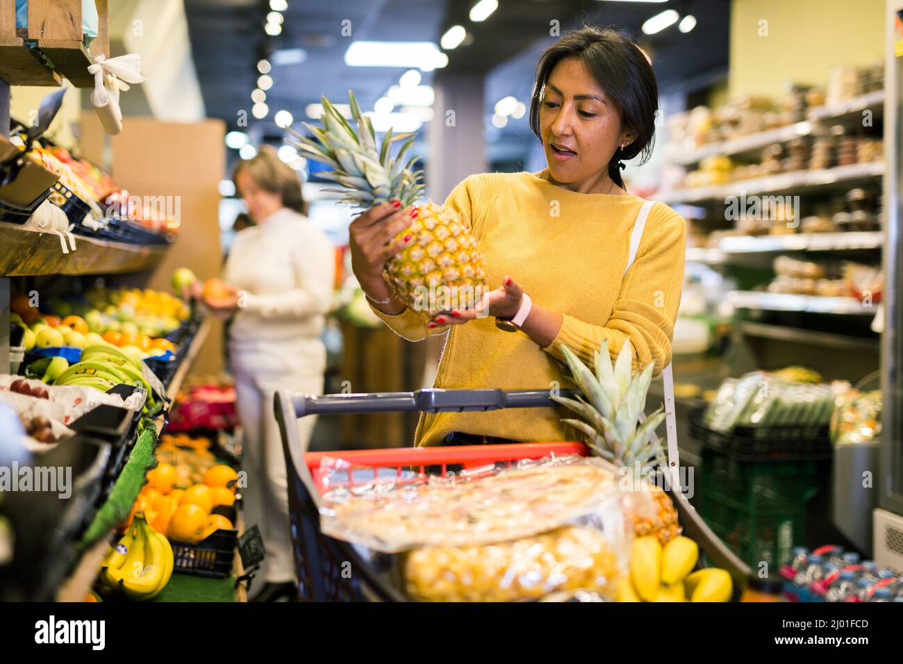 Donna che raccoglie ananas maturo al supermercato Foto Stock