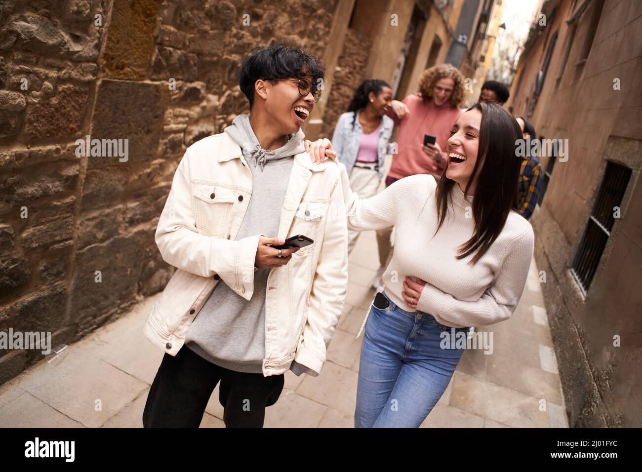 Gruppo di persone adolescenti felici che utilizzano la cella mobile all'aperto mentre si cammina al ridere. Concetto di tecnologia, amicizia e comunità Foto Stock