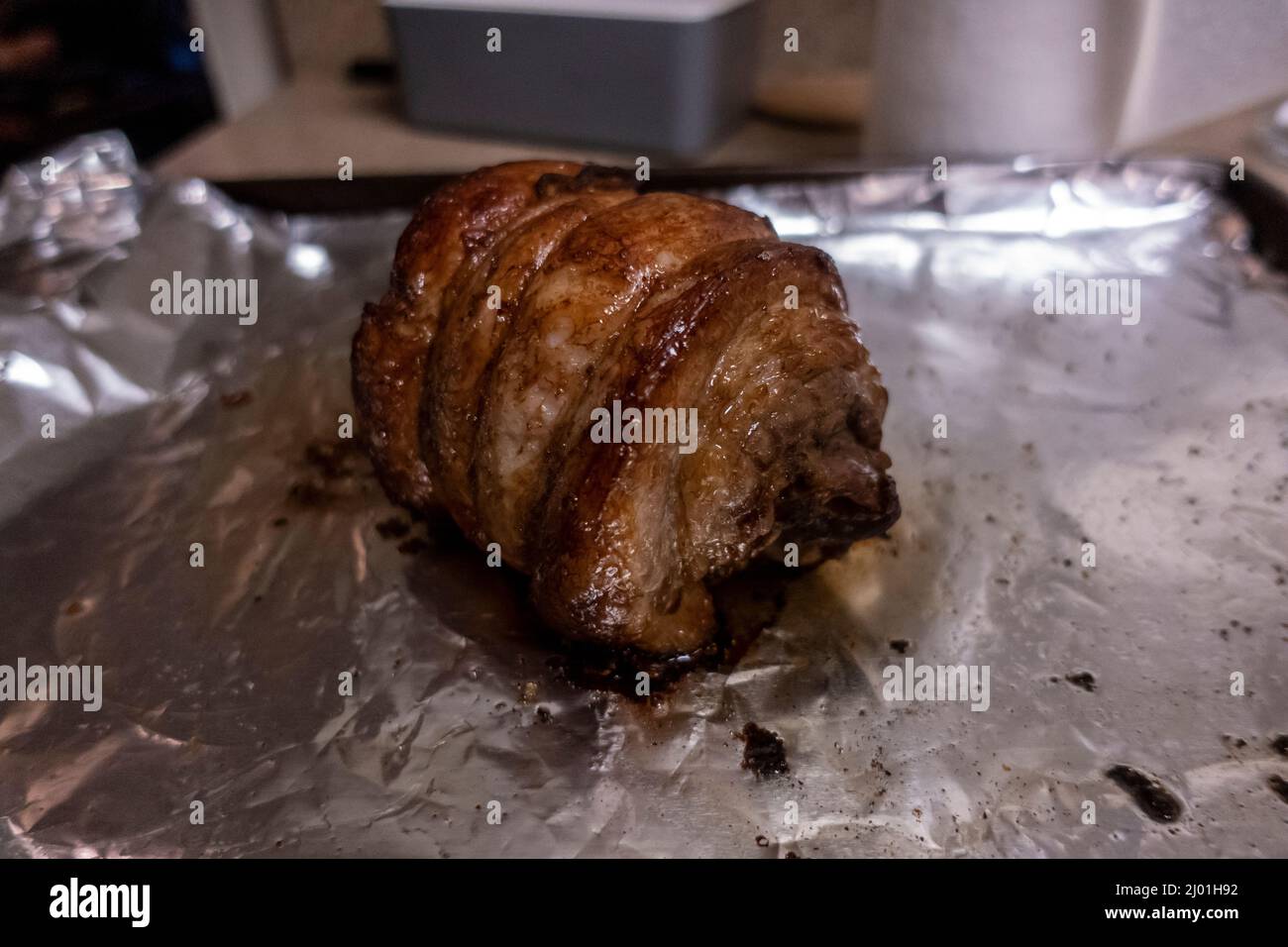 Primo piano, focalizzazione selettiva su un succoso arrosto di chashu di maiale poggiato su foglio di stagno dopo essere stato cotto Foto Stock