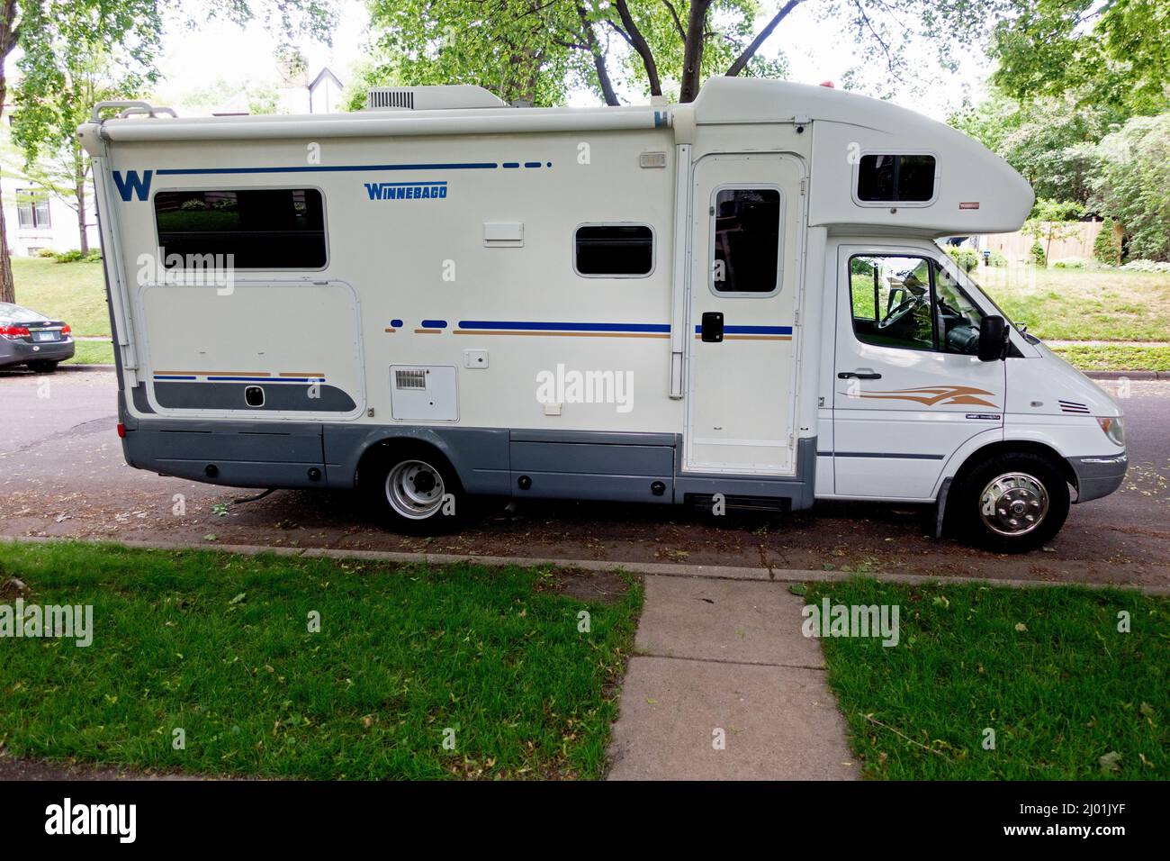 Vista laterale di un rimorchio da viaggio Winnebago parcheggiato su una strada cittadina di fronte a una casa residenziale. St Paul Minnesota, Stati Uniti Foto Stock