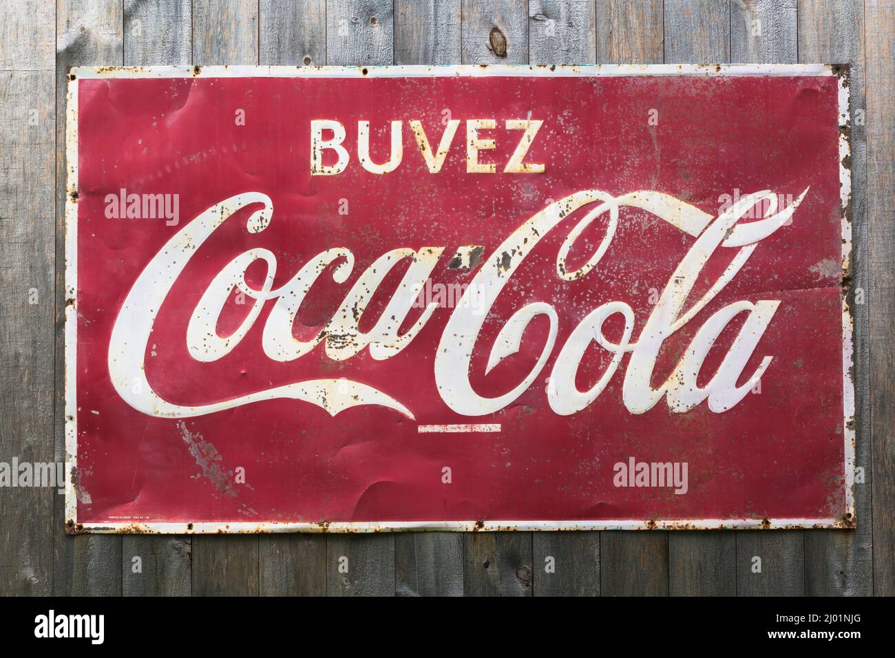 Vintage Coca Cola soft drink azienda rettangolare metallo pubblicità segno per i consumatori di lingua francese esposto su rustico legno tavola parete. Foto Stock