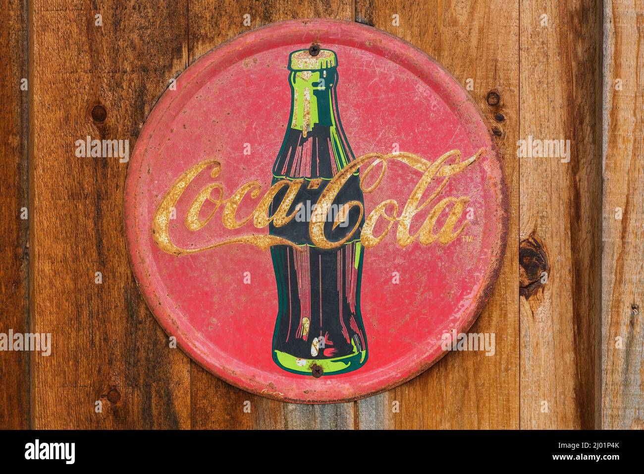 Vintage Coca Cola soft drink azienda rotondo metallo pubblicità segno apparsi su rustico legno tavola parete. Foto Stock