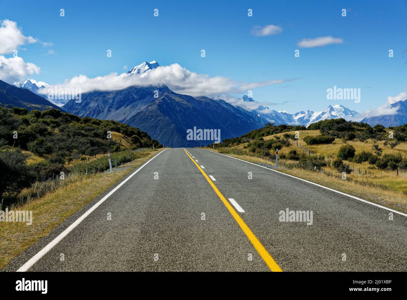 La strada che conduce al villaggio di Mount Cook, Mt Cook in background con nuvola intorno alla vetta, isola sud, Aotearoa / Nuova Zelanda. Foto Stock