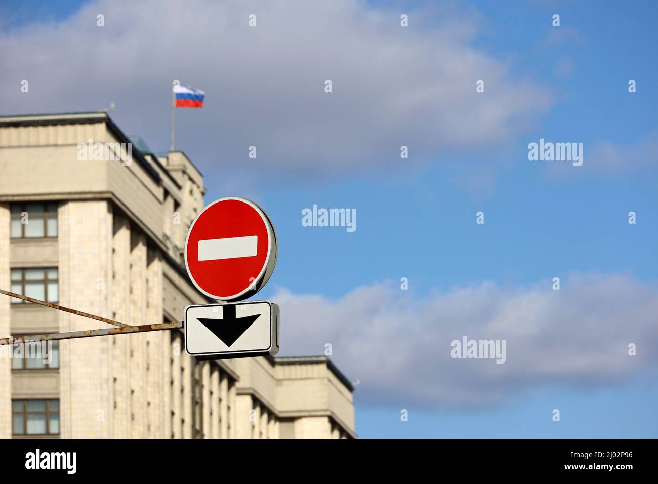 Segnale di stop sullo sfondo della Duma di Stato della Russia e bandiera russa contro il cielo blu. Concetto di sanzioni economiche dovute ad un'operazione militare speciale Foto Stock