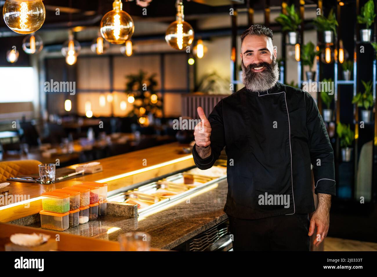 Ritratto di allegro chef sushi al ristorante sushi. Sta mostrando i pollici in su. Foto Stock