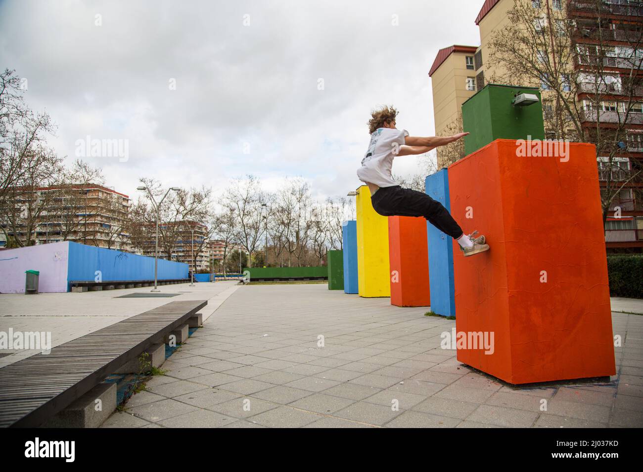 serie di foto di giovane uomo che salta praticando parkour in strada saltando tra blocchi di colore Foto Stock