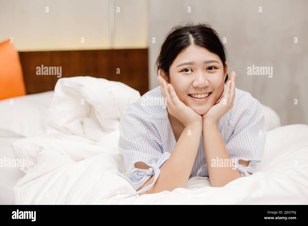 Carino ritratto sano asiatico donna pigro sorriso felice a letto Foto Stock