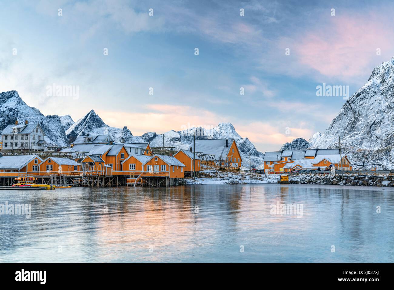 Le cabine di legno dei pescatori ricoperte di neve al tramonto nel piccolo villaggio di Sakrisoy, Reine, Nordland, Isole Lofoten, Norvegia, Scandinavia, Europa Foto Stock