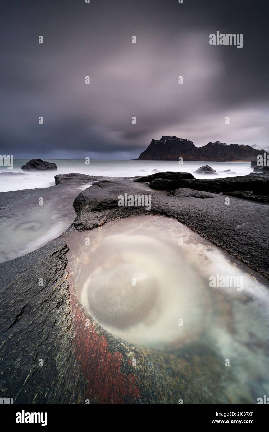 Nuvole di tempesta sopra la formazione di roccia dell'occhio lavata dalle onde, Utttakleiv, Leknes, Vestvagoy, Nordland, Isole Lofoten, Norvegia, Scandinavia, Europa Foto Stock