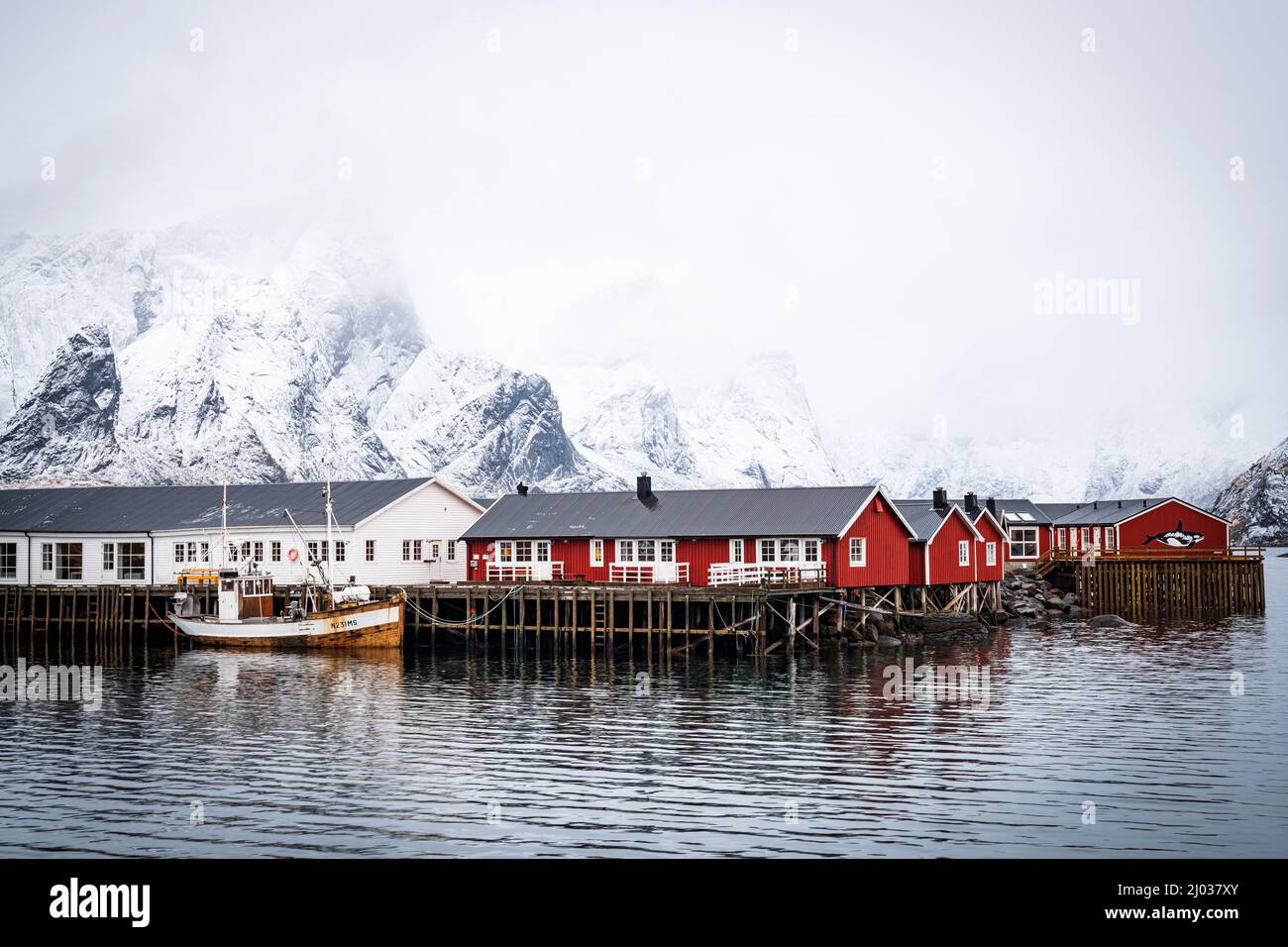 Cielo foggy sulle montagne innevate e le tradizionali cabine di Rorbu sul mare, Hamnoy, contea di Nordland, Isole Lofoten, Norvegia, Scandinavia, Europa Foto Stock