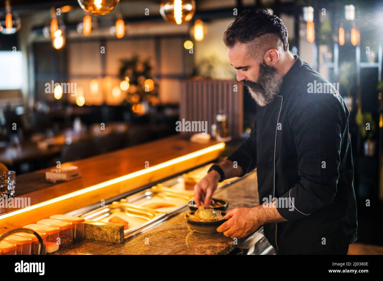 Il sushi chef prepara il dessert al sushi bar. Foto Stock