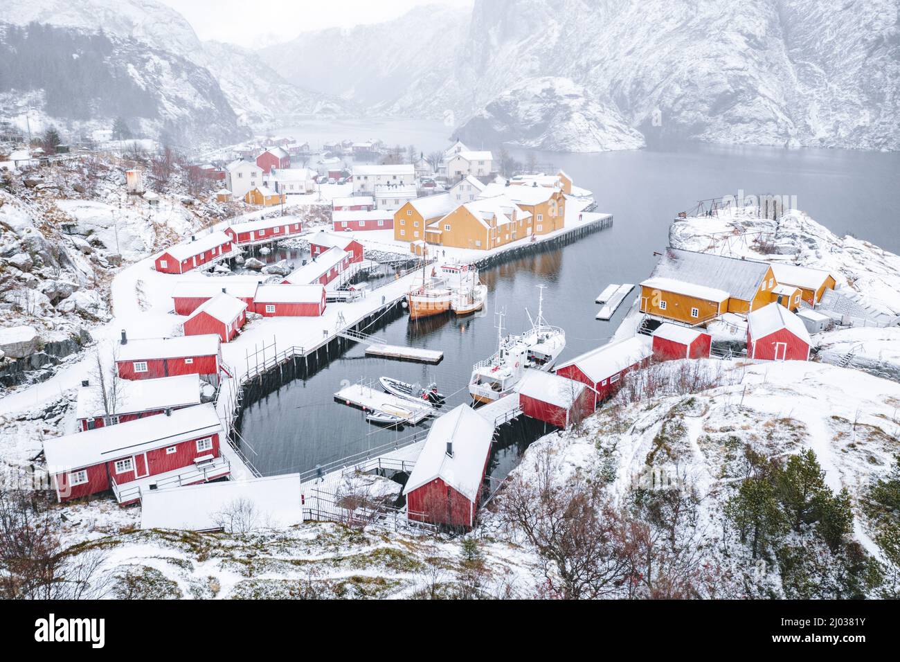 Vista ad alto angolo delle cabine dei pescatori tradizionali e del porto coperto di neve, del Nusfjord, del Nordland, delle isole Lofoten, della Norvegia, Scandinavia, Europa Foto Stock