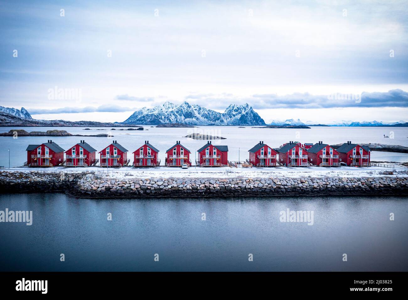Vista aerea delle cabine rosse di rorbu in fila tra il mare freddo in inverno, Svolvaer, contea di Nordland, Isole Lofoten, Norvegia, Scandinavia, Europa Foto Stock