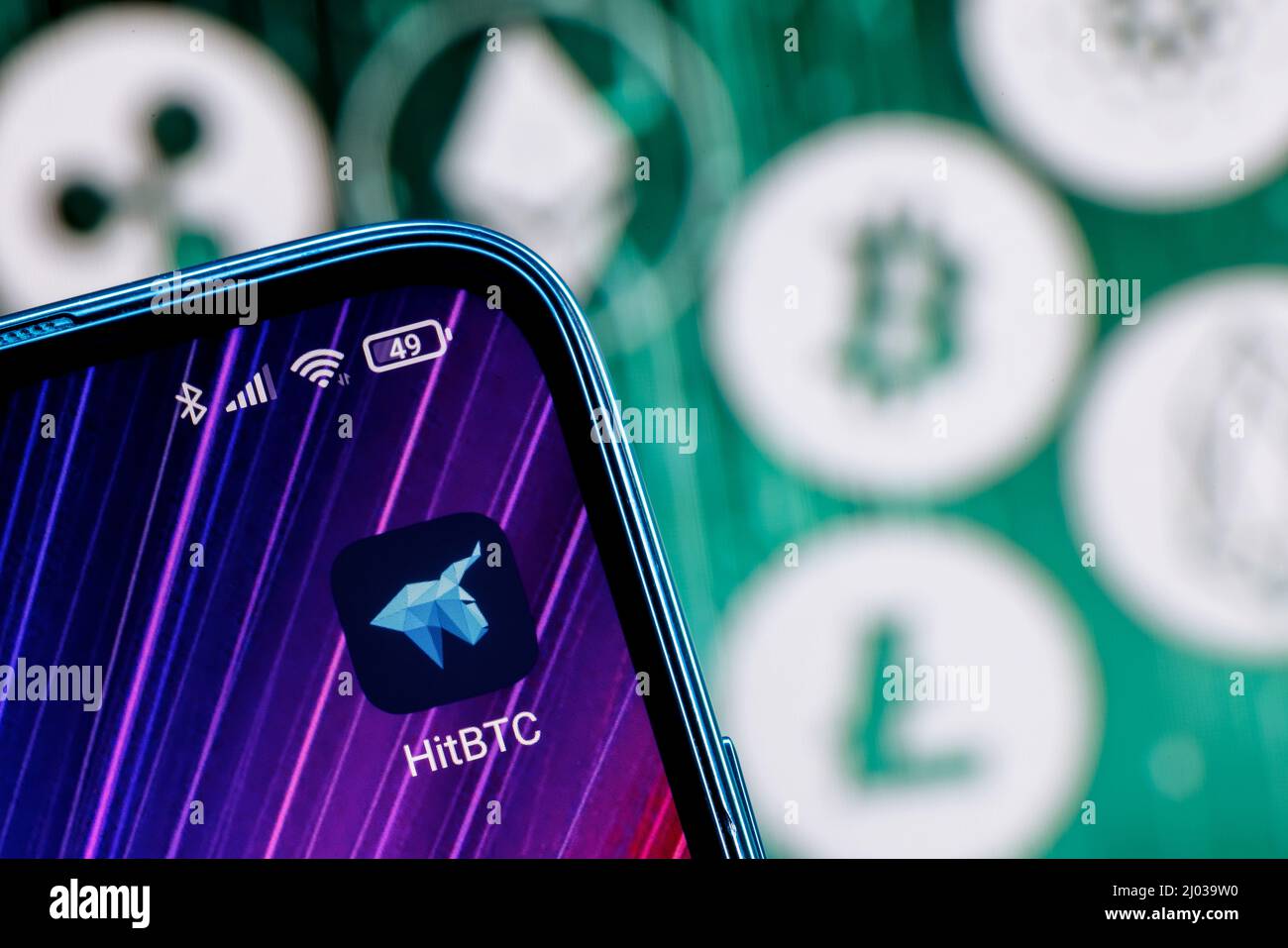 HitBTC è uno scambio di criptovaluta. App HitBTC sullo schermo dello smartphone sullo sfondo delle principali criptovalute. Foto Stock