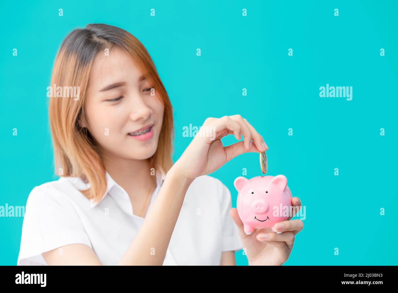 Carino università Asian teen ragazza felice risparmio soldi con sorriso Piggy banca Foto Stock