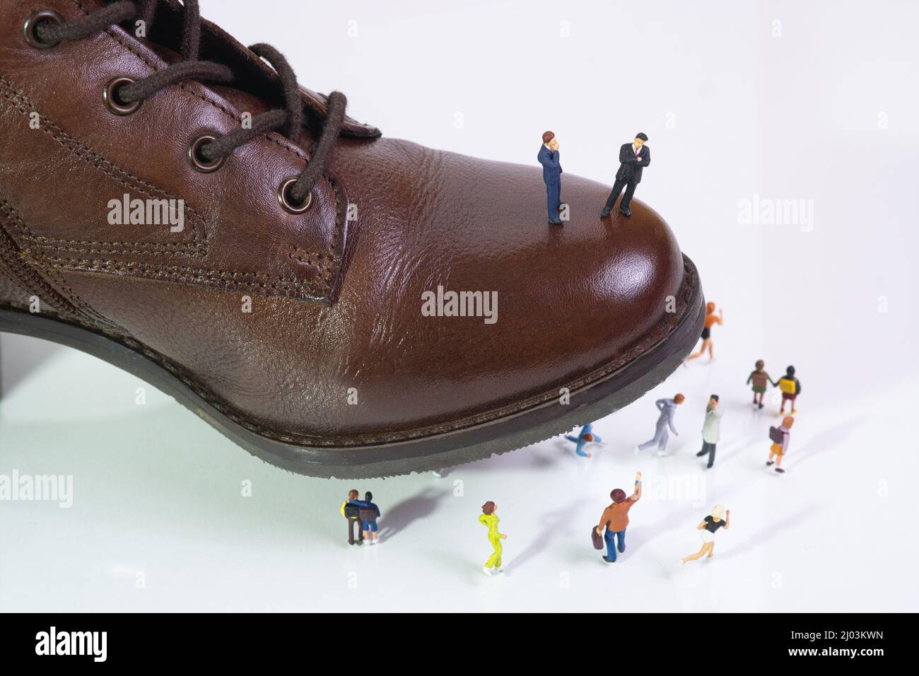 Due potenti uomini d'affari si levano in piedi su una scarpa che passi sulla gente in fuga Foto Stock