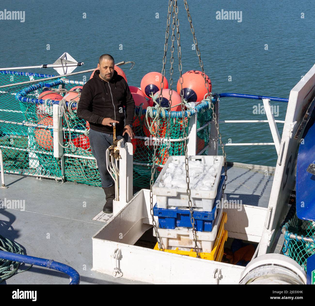 Pescatore che scarica scatole di pesce da pesca pescatore pescatore stiva. Foto Stock