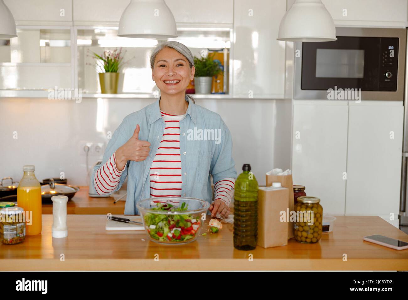 Donna allegra che approva insalata di verdure fresche in cucina Foto Stock