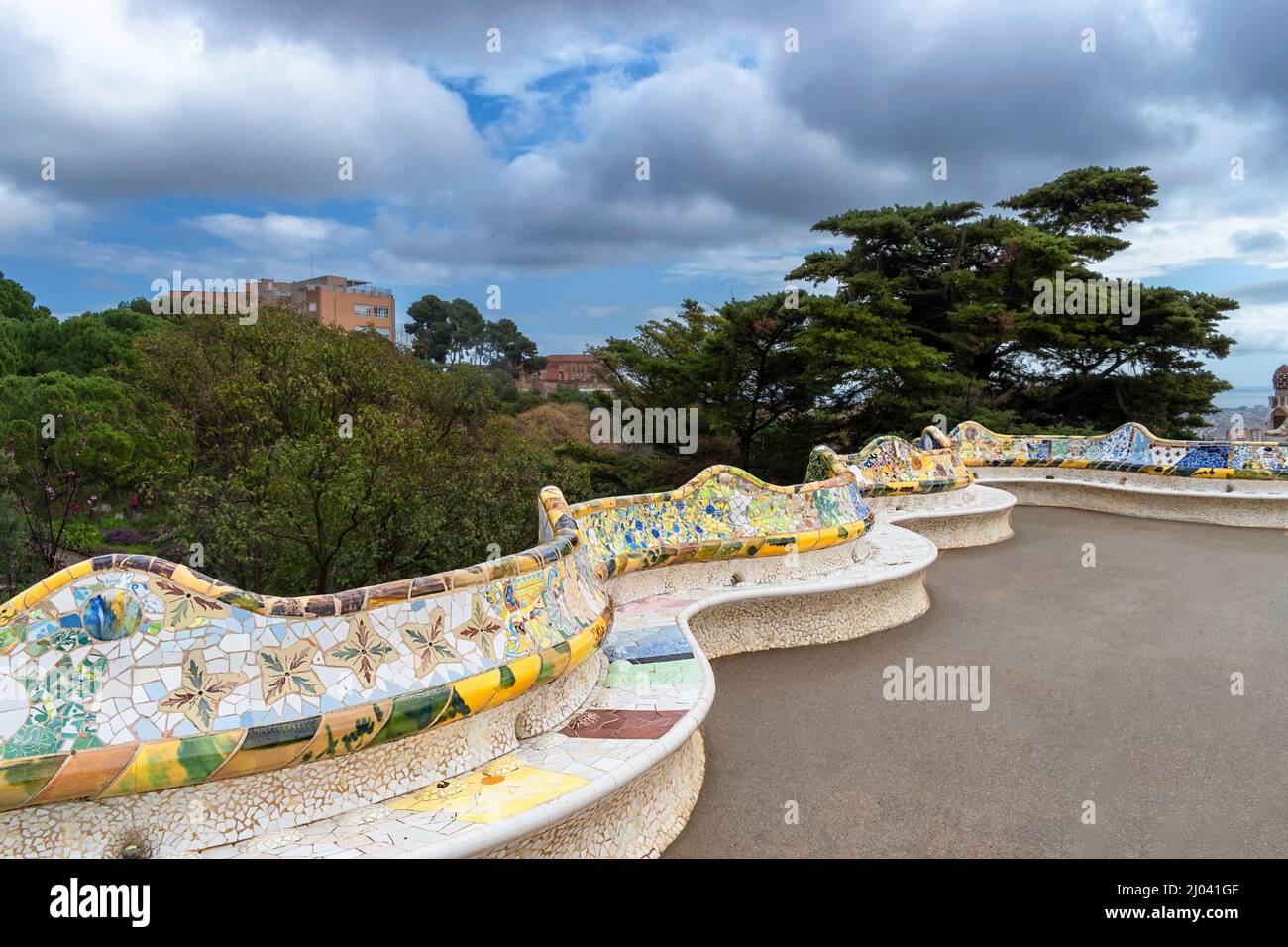 PARK GUELL BARCELLONA CATALOGNA SPAGNA TERRAZZA CENTRALE GAUDI TRENCADIS MOSAICI GIALLI E VERDI SU SEDILI A SERPENTINA O PANCHINE Foto Stock