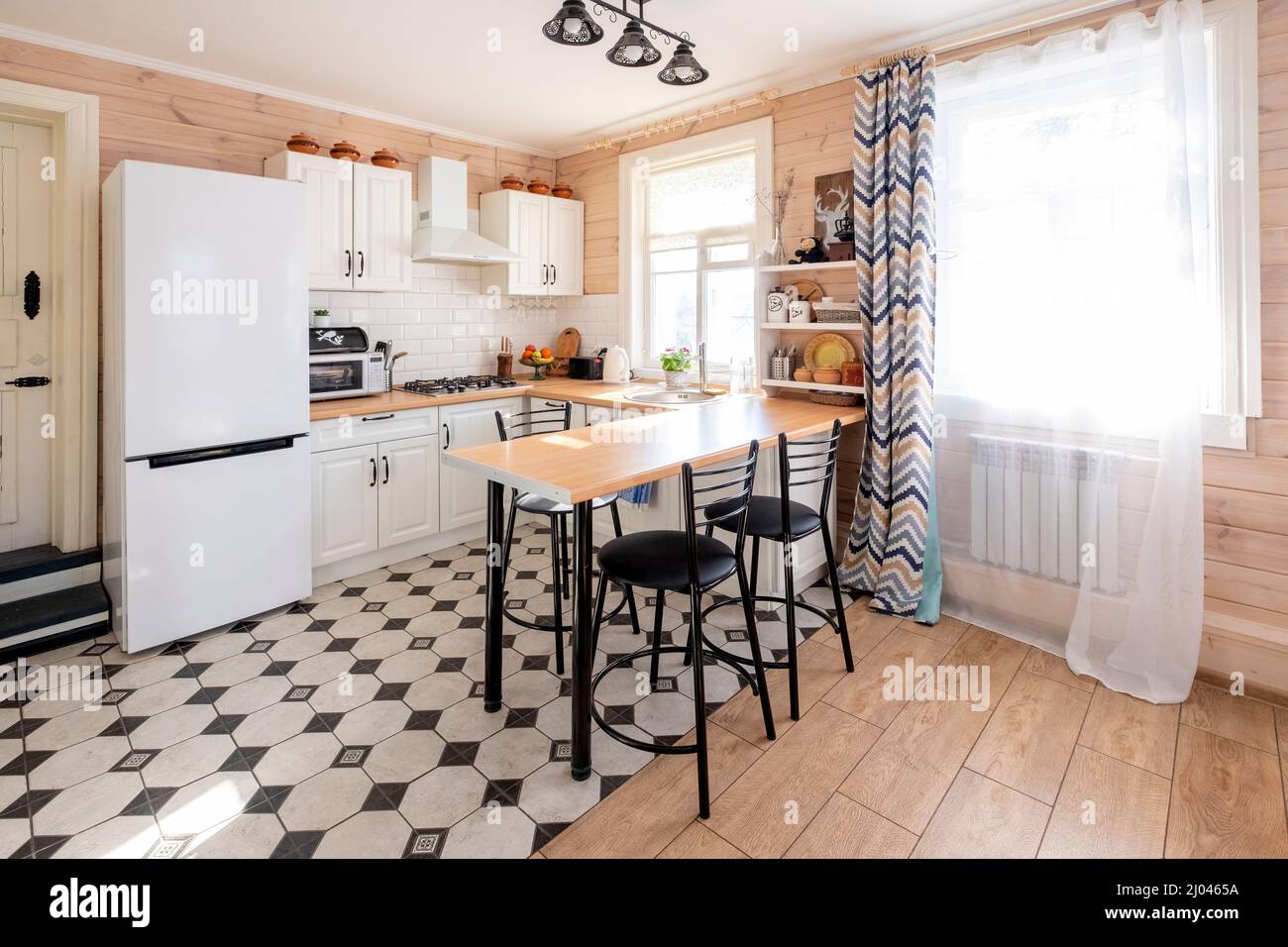Moderna cucina bianca a forma di U in stile scandinavo. In una luminosa casa rustica dove la cucina è combinata con il soggiorno Foto Stock