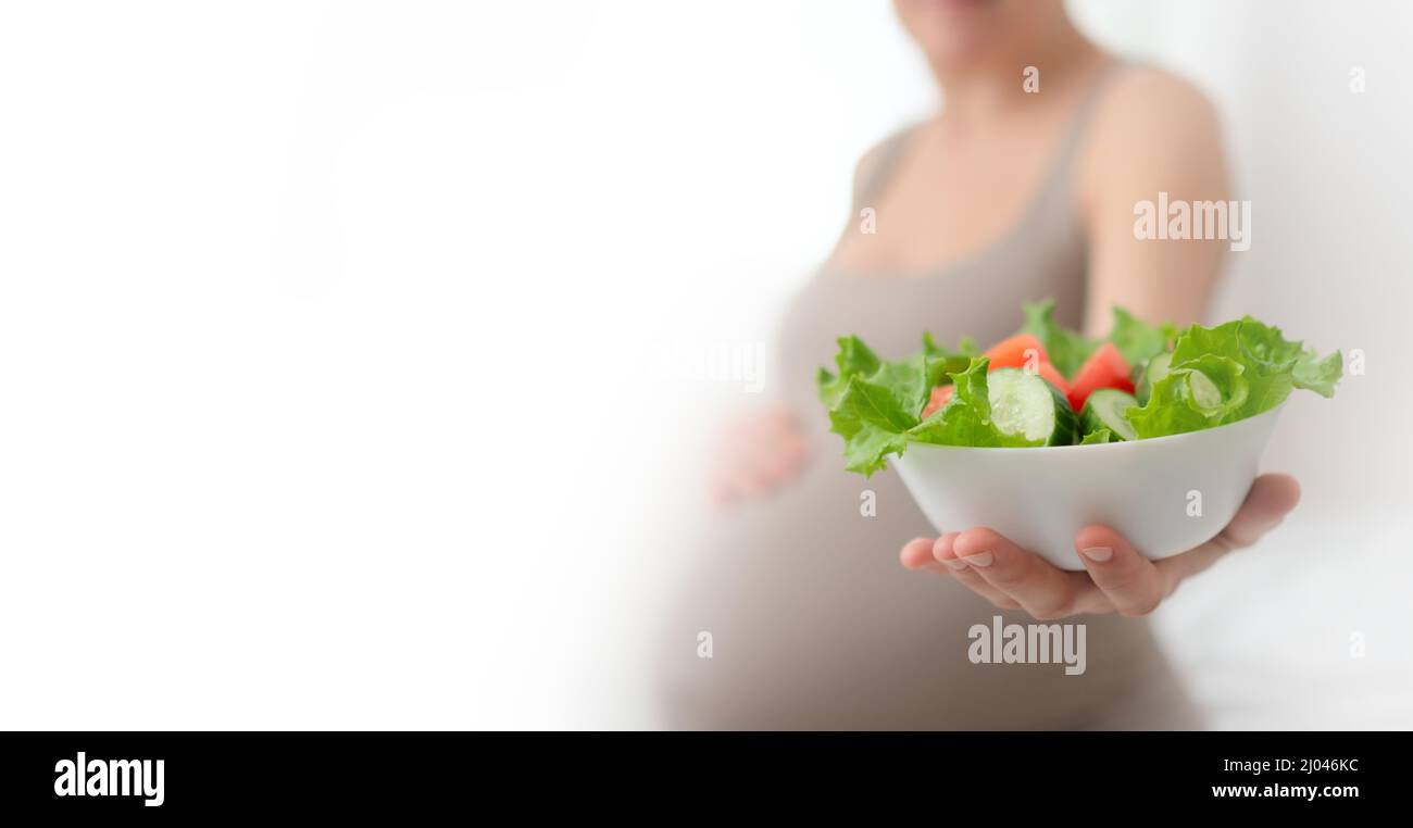 La donna incinta tiene in mano verdure fresche. Il concetto di alimentazione sana durante la gravidanza. Assistenza sanitaria durante il parto. Cibo e una dieta variata di verdure per la madre in attesa. Foto Stock