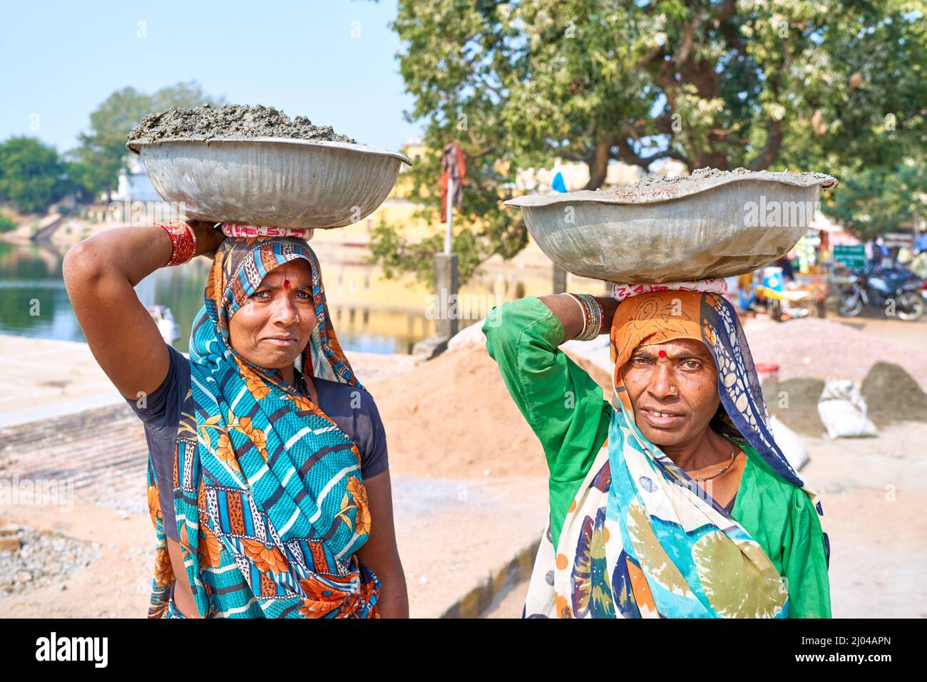 India. Varanasi. Due donne che trasportano un carico sopra la loro testa Foto Stock