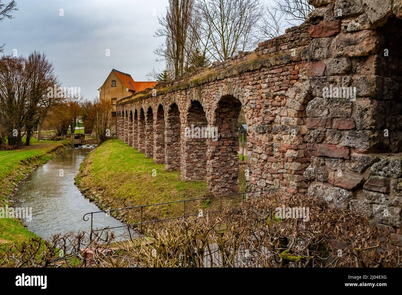 Splendida vista degli archi delle rovine artificiali dell'acquedotto romano lungo il torrente Leimbach che serve anche come confine per la... Foto Stock