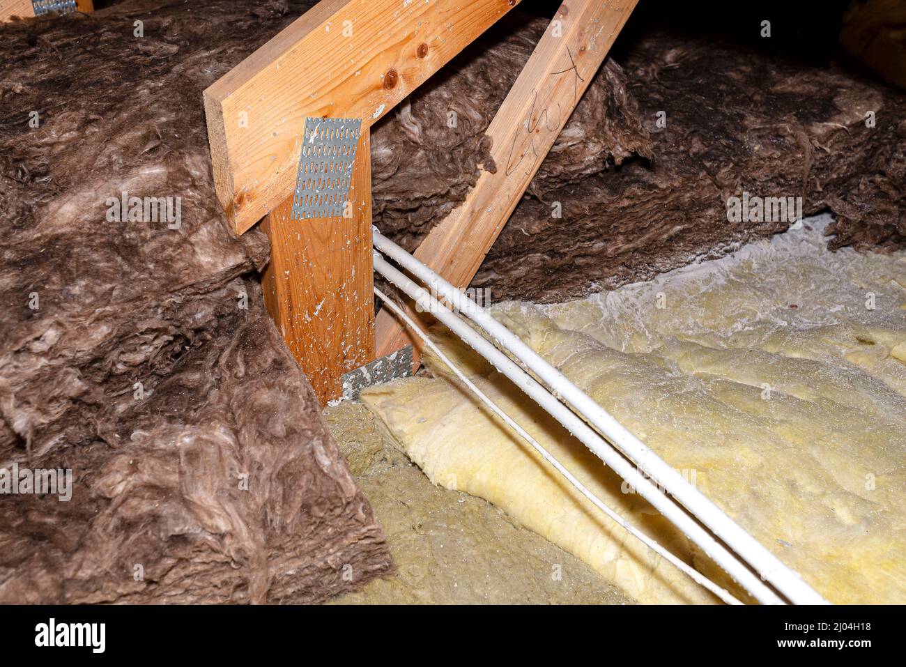 Cavo elettrico in un tubo PCV sul traliccio del tetto nella soffitta della casa. Foto Stock