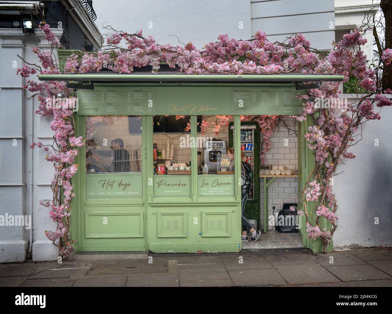 Street cafe a Notting Hill, Londra circondato da ciliegi in fiore. Foto Stock