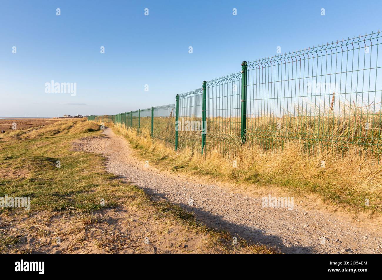 West Kirby, Regno Unito: Sentiero costiero vicino alla recinzione del confine metallico del campo da golf Royal Liverpool (Hoylake) sulla penisola di Wirral. Foto Stock