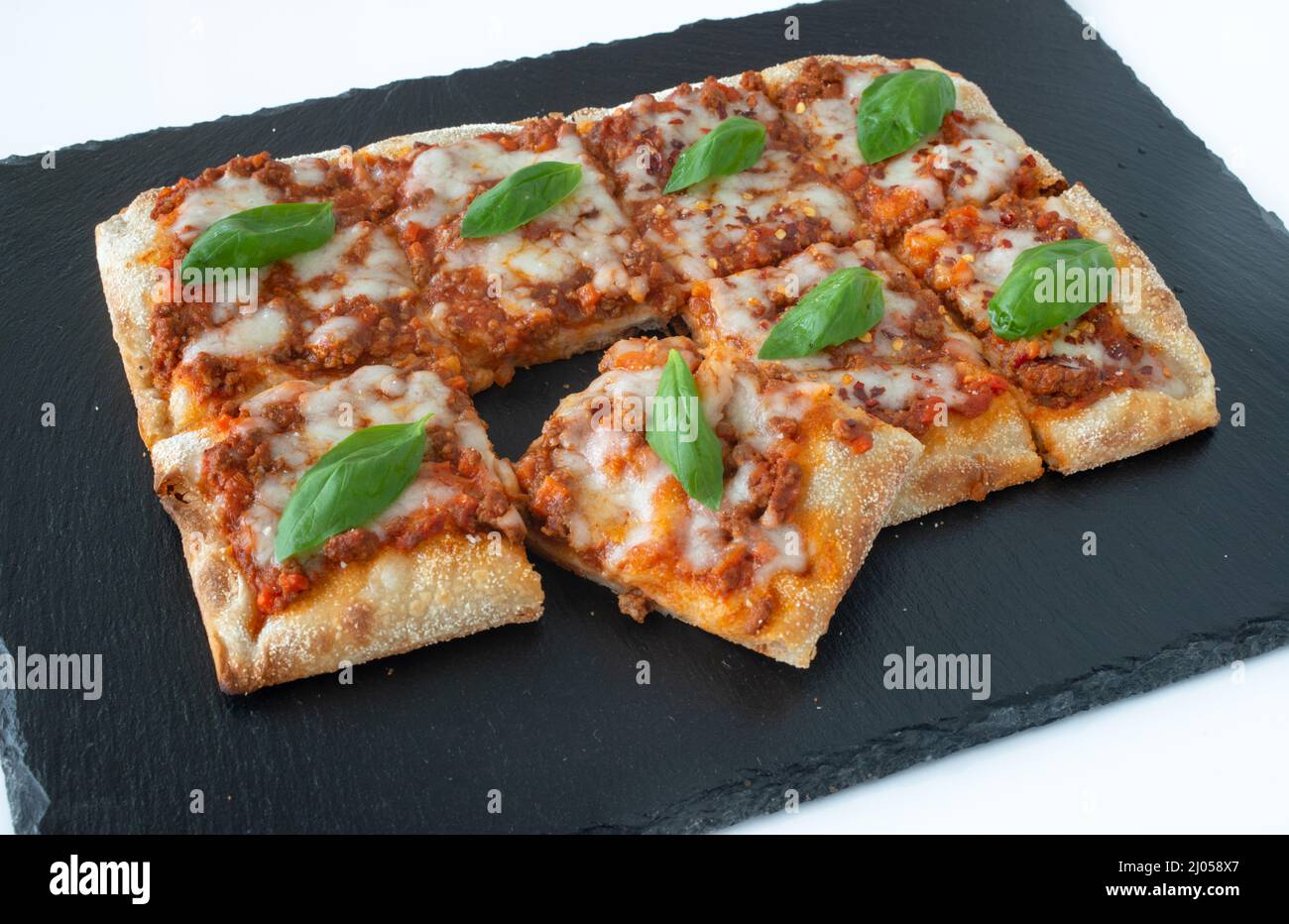 Pizza a taglio su sfondo di pietra nera Foto Stock