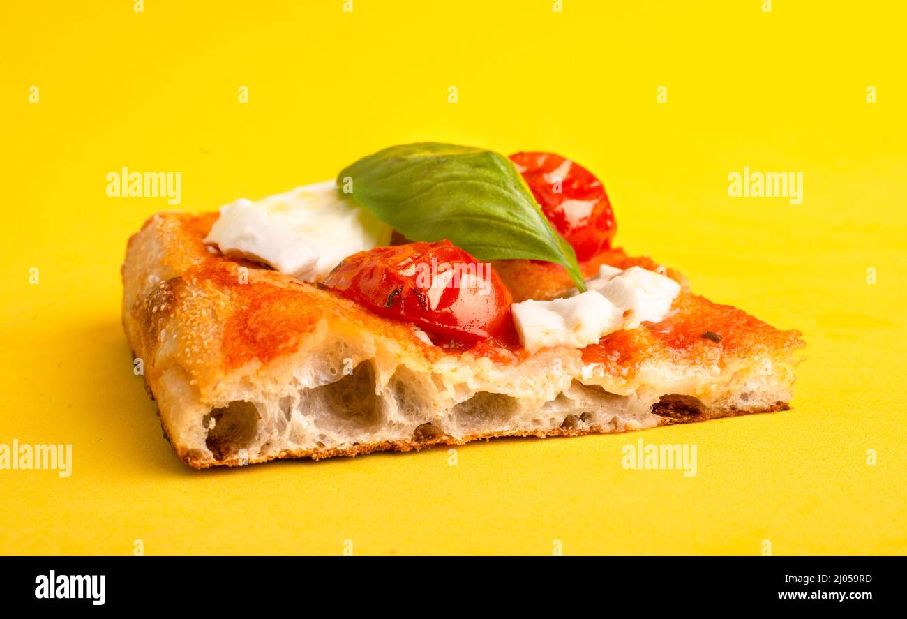 Un pezzo di pizza al taglio con pomodoro e mozzarella isolato su sfondo giallo Foto Stock