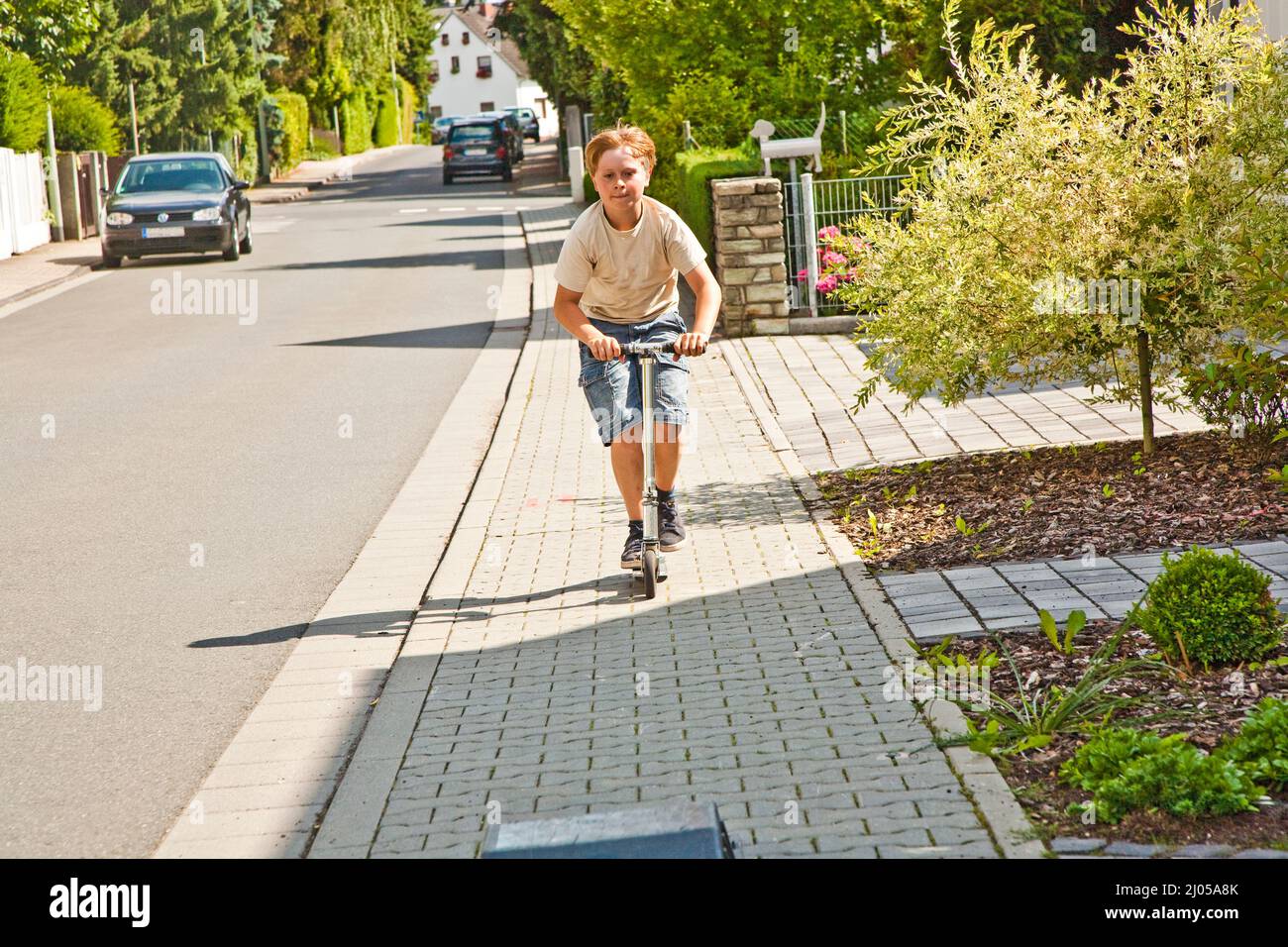 il ragazzo guida lo scooter sul paveway in una strada Foto Stock