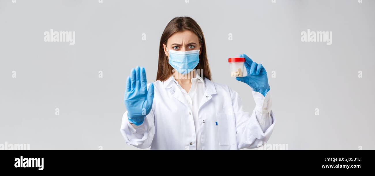 Covid-19, prevenzione di virus, operatori sanitari e concetto di quarantena. Serio medico interessato in maschera medica e DPI, dire di smettere di usare queste pillole Foto Stock