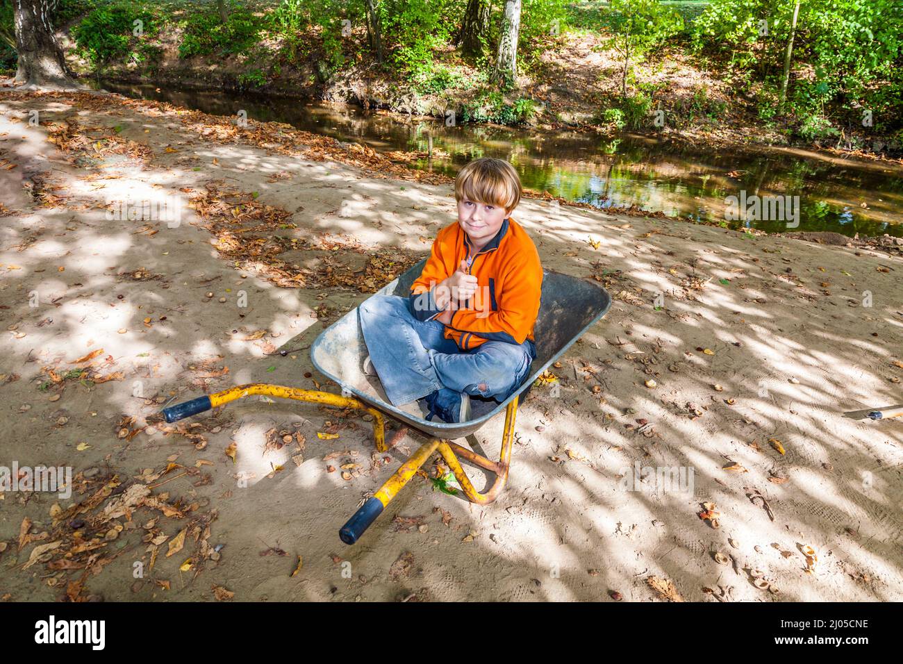 Carino il bambino si siede nella ruota barrow e rilassa Foto Stock
