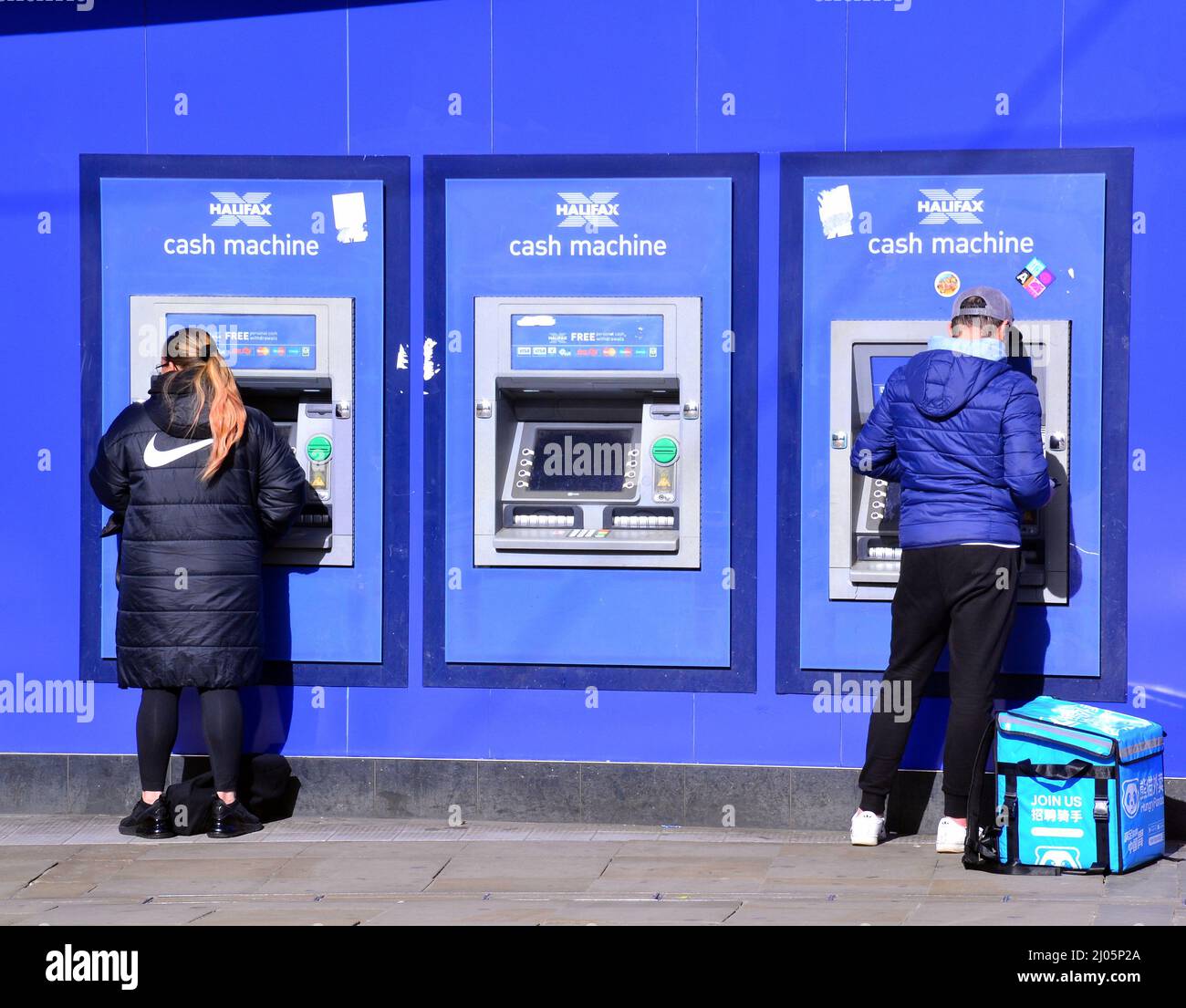 Le persone usano bancomat Halifax o bancomat automatico a Piccadilly, nel centro di Manchester, Regno Unito Foto Stock