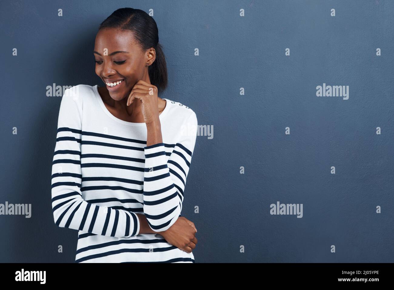 Shes sul lato timido. Scatto di una giovane donna attraente sorridente timidamente su uno sfondo grigio. Foto Stock