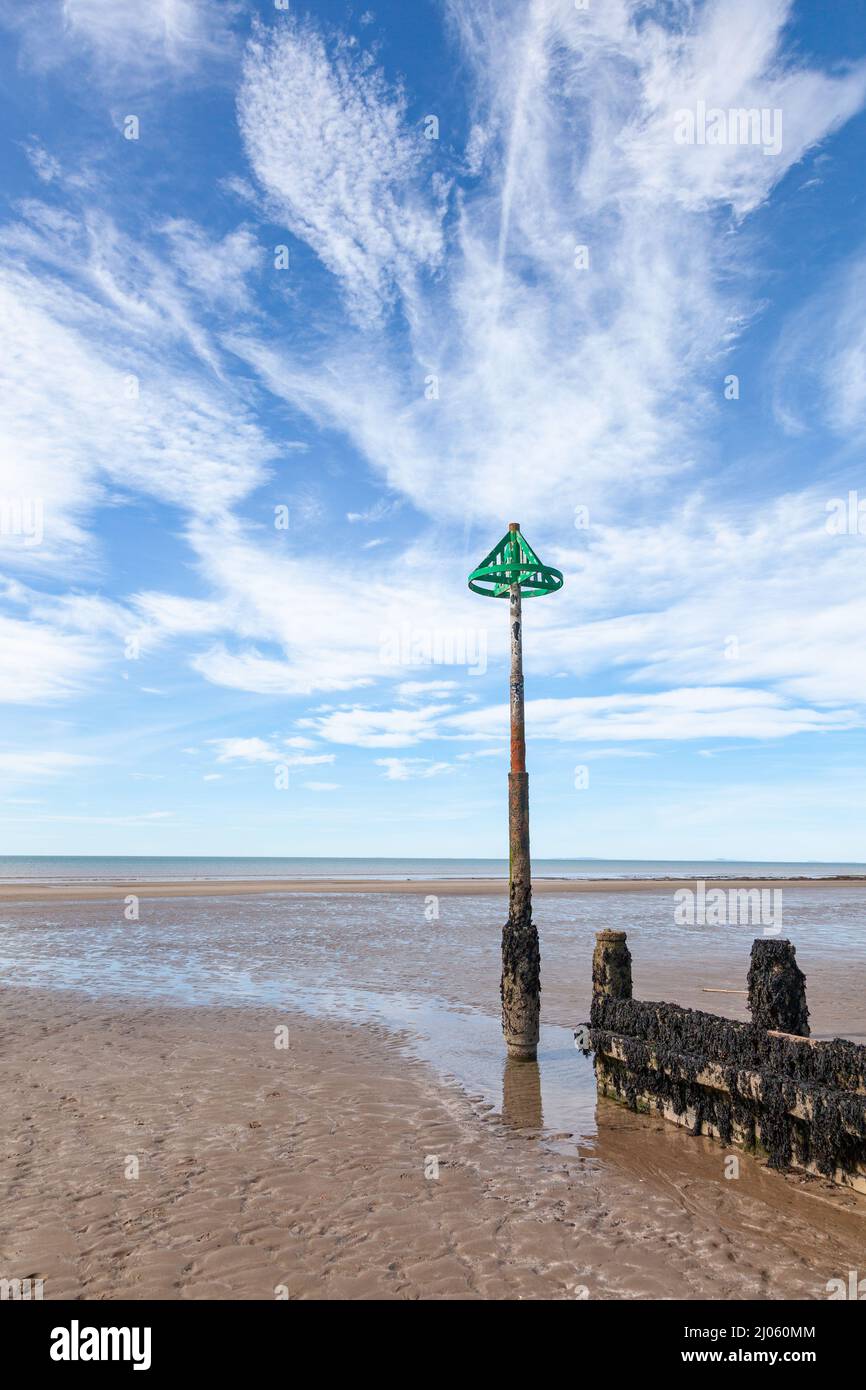 Groyne di legno e l'estremità alta del marcatore groyne sulla spiaggia di sabbia contro il cielo di nuvola di cirrus sfondo Foto Stock