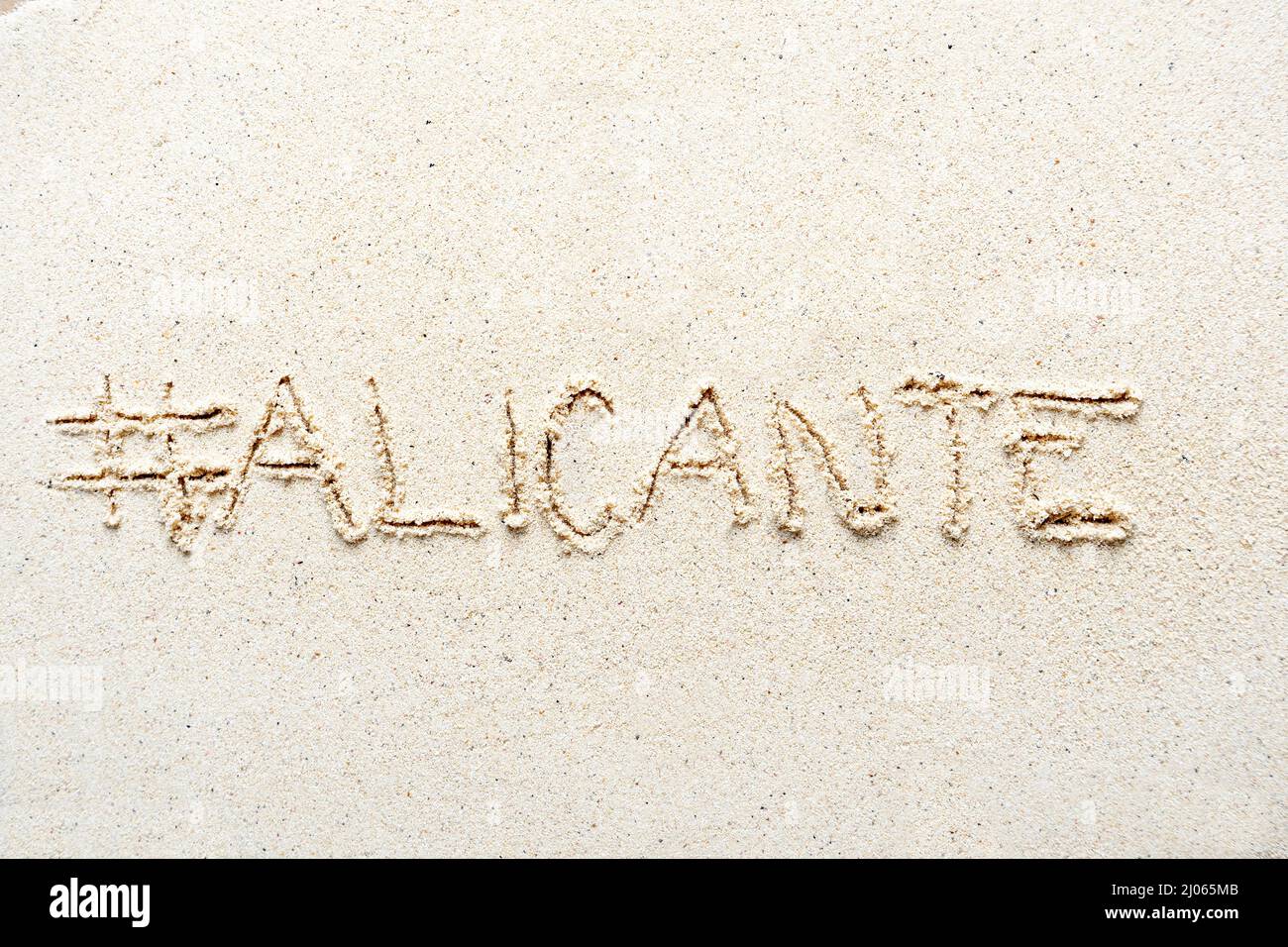 Scrivere a mano le parole 'Alicante' sulla sabbia della spiaggia Foto Stock