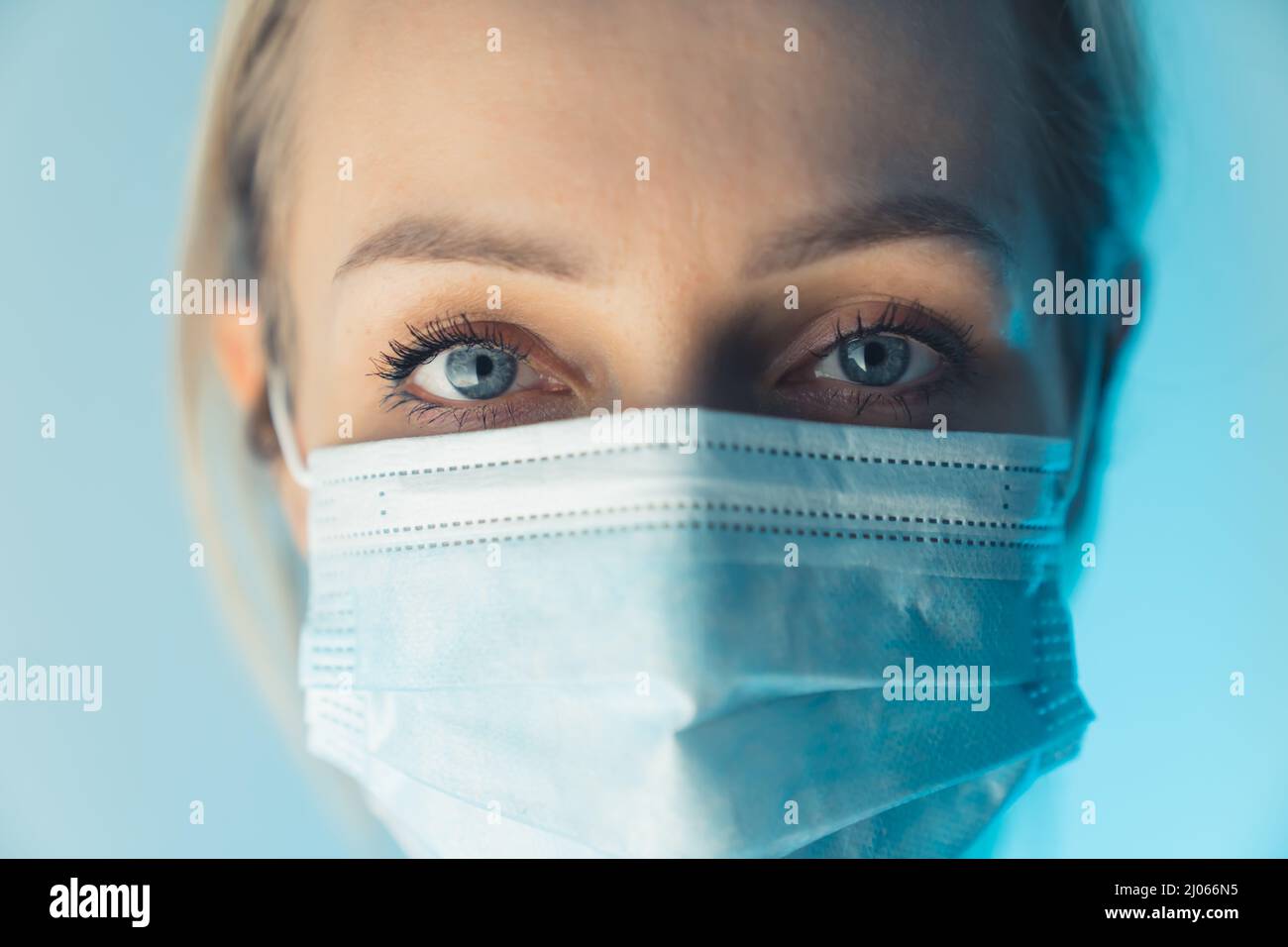 Stanchezza agli occhi dell'operatore sanitario europeo. Primo piano studio girato donna caucasica indossando maschera chirurgica. Foto di alta qualità Foto Stock