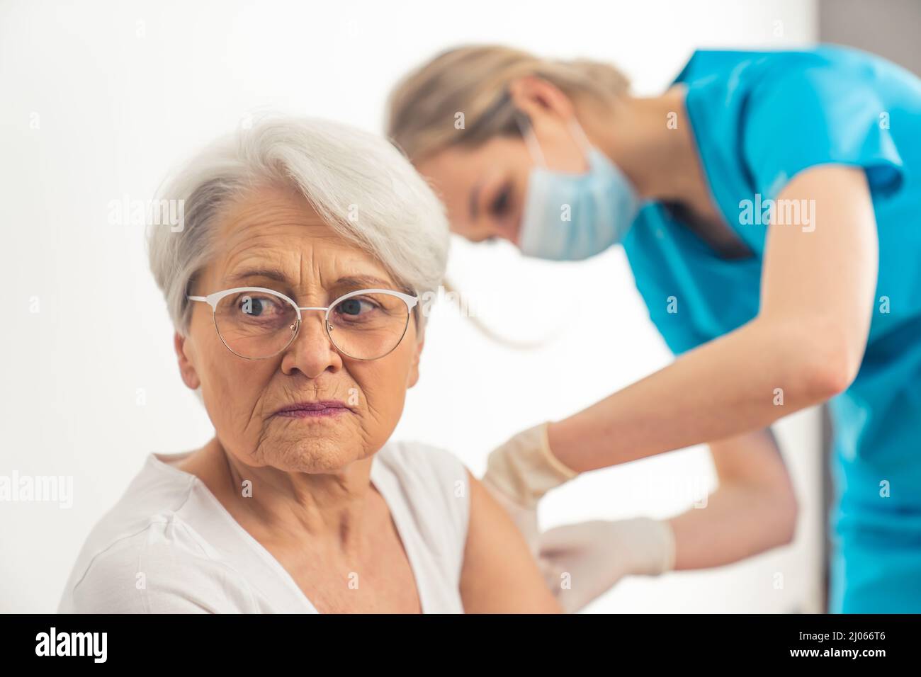 Donna caucasica anziana temuta di essere infetta, decide di vaccinarsi con l'aiuto di una giovane infermiera. Foto di alta qualità Foto Stock