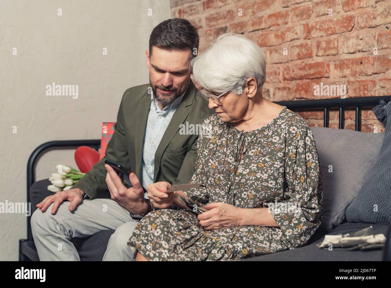 parenti caucasici con differenze di età confrontando le fotografie stampate con quelle scattate con lo smartphone. Foto di alta qualità Foto Stock