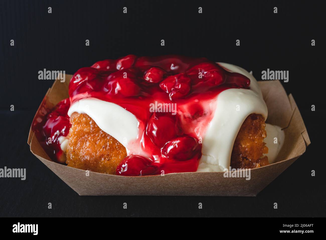 Rotolo di cannella Frosted Cherry da vicino su sfondo nero Foto Stock