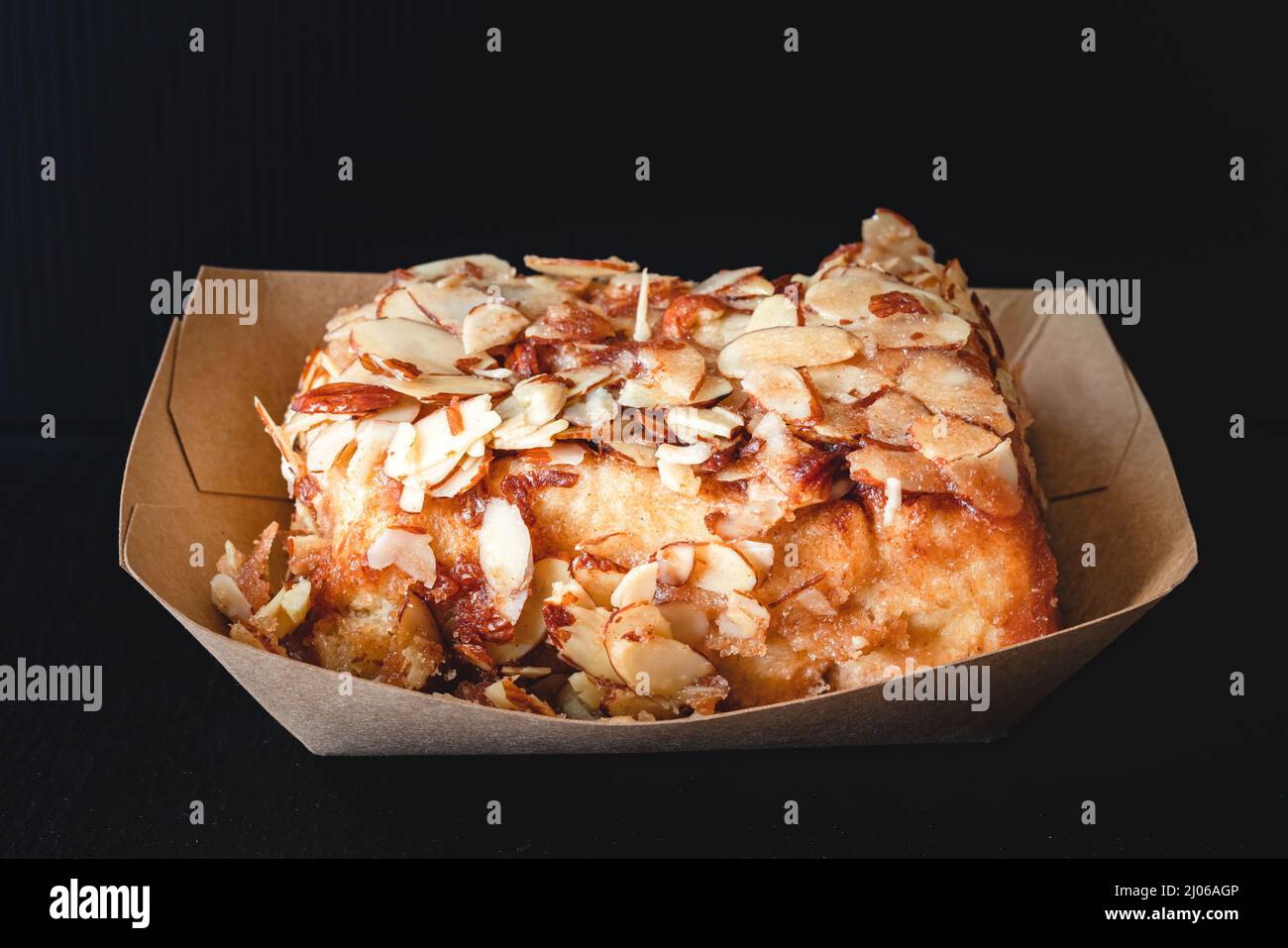 Rotolo di cannella ghiacciato di mandorla da vicino su sfondo nero Foto Stock