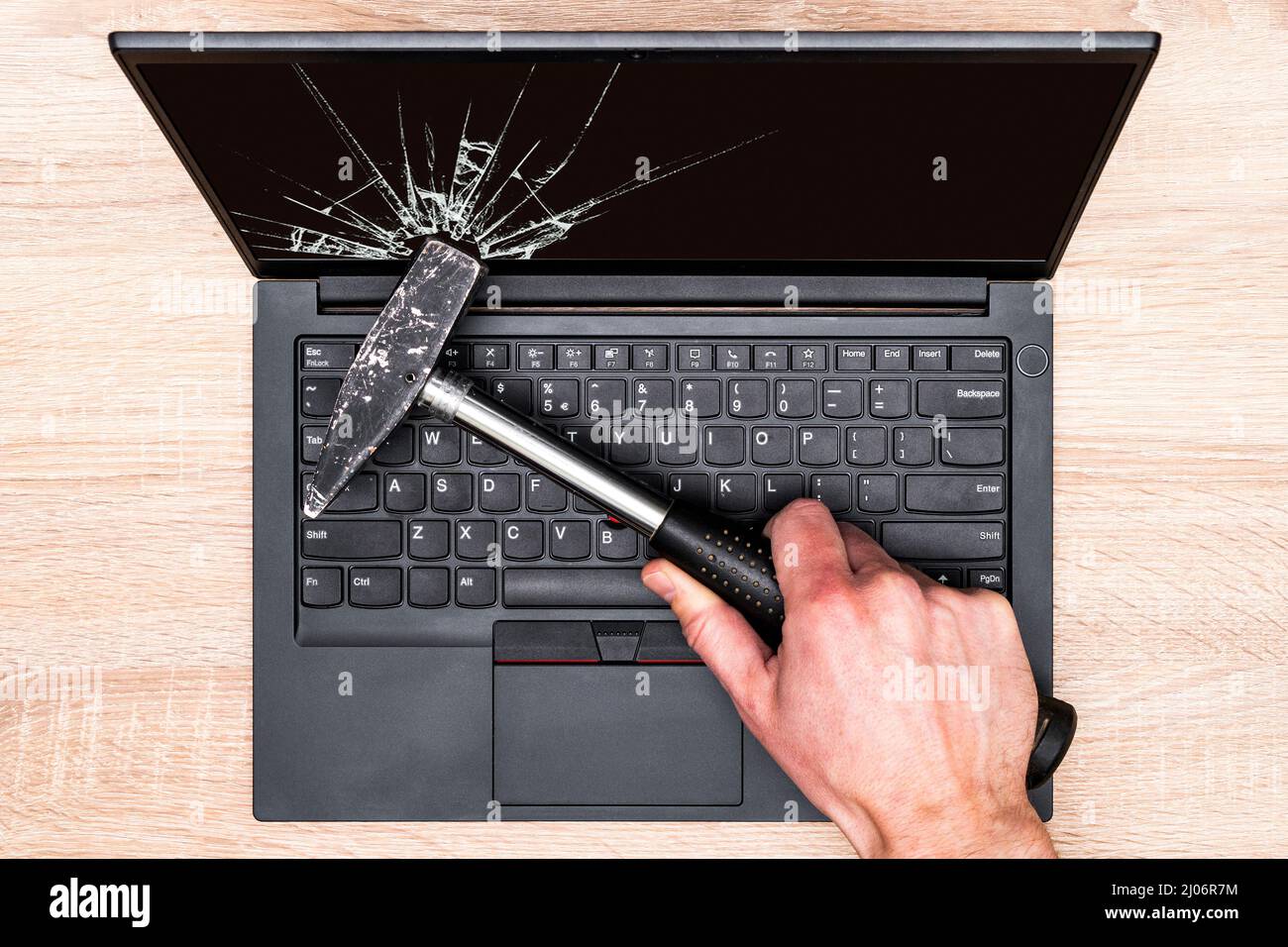 Schermo portatile che si rompe a mano con un martello. Concetto di riparazione grossolana delle apparecchiature informatiche. Foto Stock