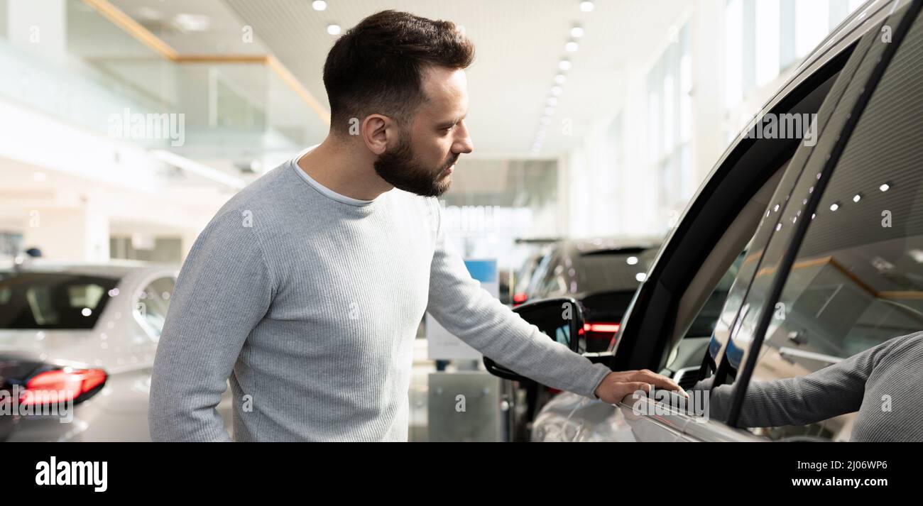 l'acquirente maschile sceglie una nuova auto in una concessionaria auto ispeziona la vettura Foto Stock