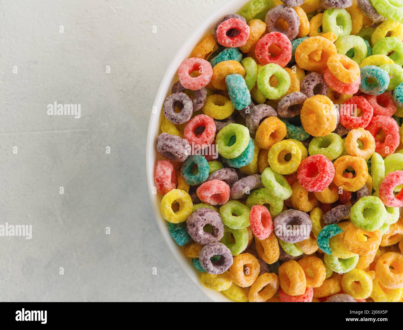 Vista ad angolo alto. Anelli colorati di grano intero in una grande ciotola. Primo piano. Colazione a cereali. Supermercato, pasticceria, pubblicità, banne Foto Stock