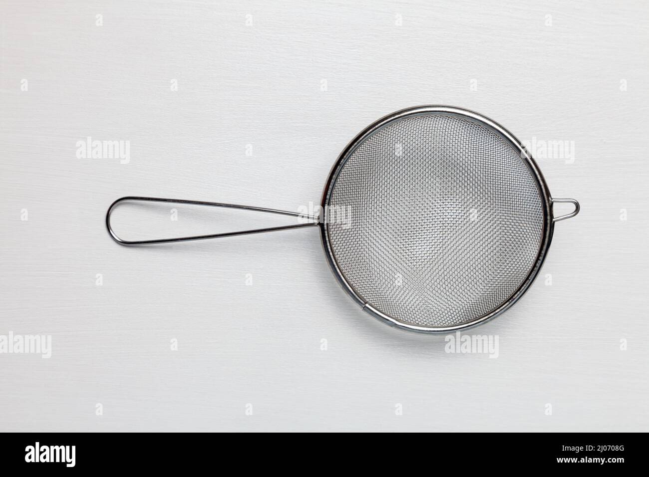 Setaccio da cucina in acciaio inox con manico sfondo bianco Foto Stock